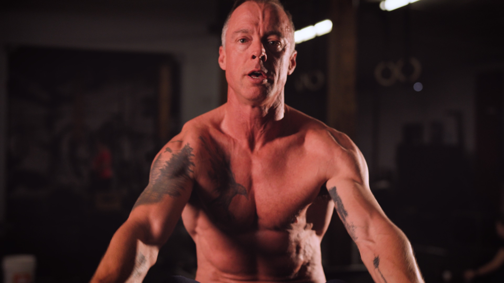 An athlete in a gym, lit against an out-of-focus training space.