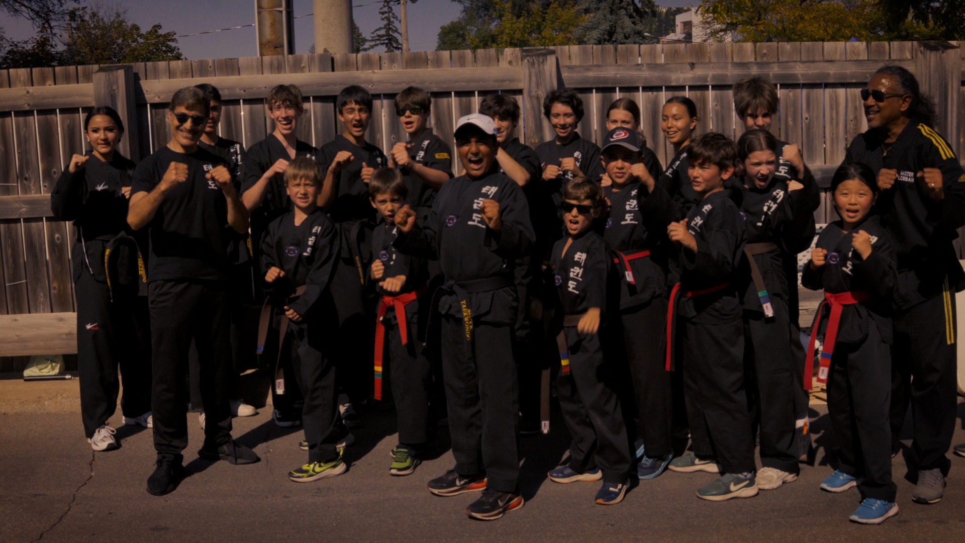 A martial arts group standing together outdoors in their training uniforms.
