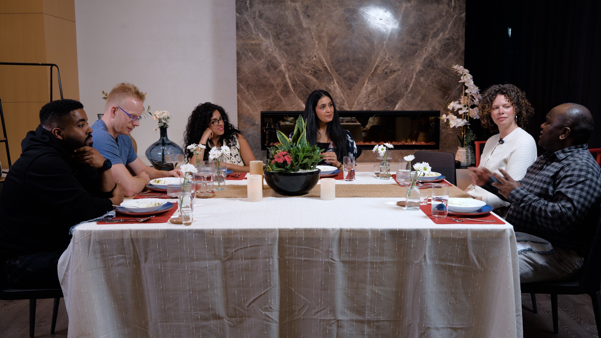 Six people sharing a conversation around a dining table.